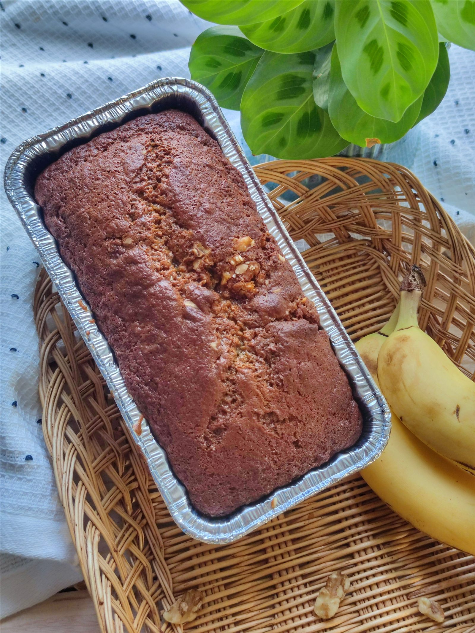 A freshly baked banana cake beside ripe bananas