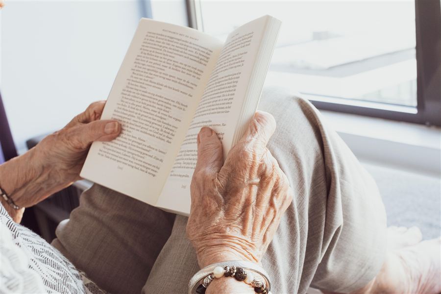 Elderly hands holding an open book — a quiet moment of presence and intention