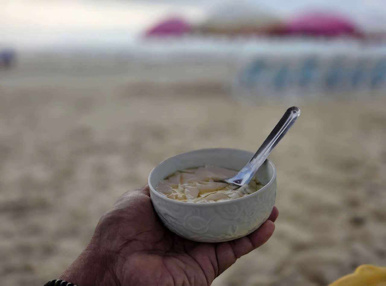 A bowl of warm curd tofu at the water's edge