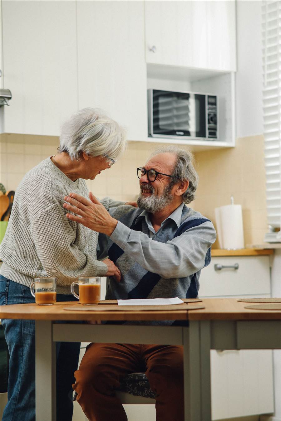 Senior couple embracing and smiling in their kitchen — warmth and togetherness at home
